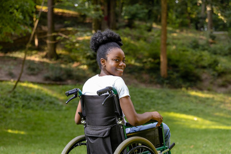 African american young woman on a wheelchair in the parkの写真素材