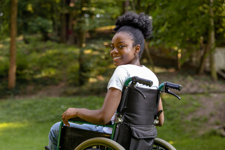 African american young woman on a wheelchair in the parkの写真素材