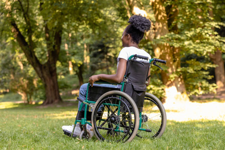Young dark-skinned woman sitting on a wheelchair and smiling nicely