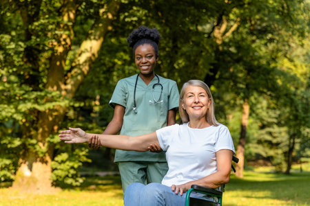 Female on a wheelchair looking contented while having a walk with a nurse in the parkの写真素材