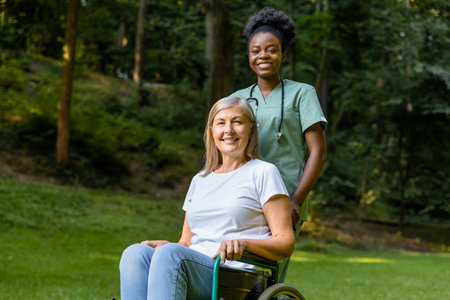 Female on a wheelchair looking contented while having a walk with a nurse in the parkの写真素材