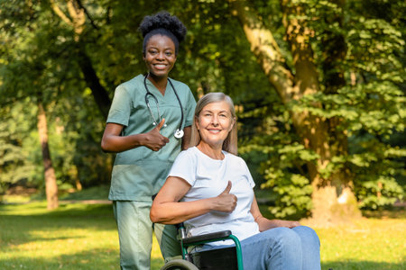 Female on a wheelchair looking contented while having a walk with a nurse in the parkの写真素材