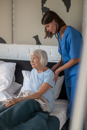 Doctor examining elderly patient and looking concentratedの写真素材
