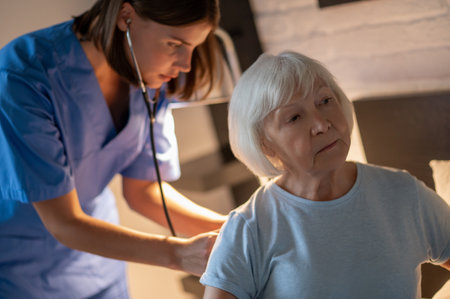 Doctor examining elderly patient and looking concentratedの写真素材