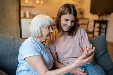 Volunteer and senior woman watching something on the phoneの写真素材