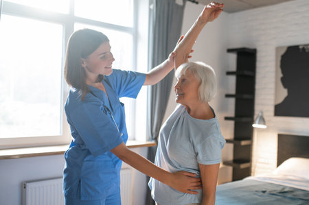 Elderly lady exercising with an instructor and looking involvedの写真素材