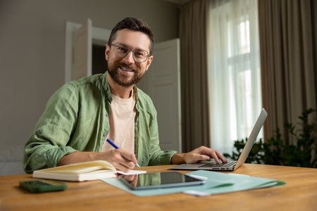 Bearded man analyzing reports in home officeの写真素材
