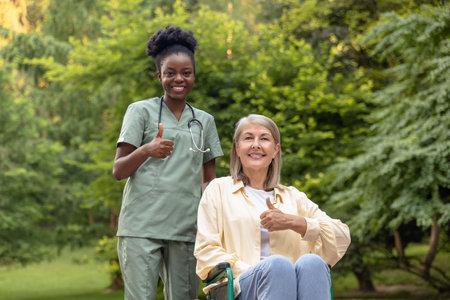 Woman on a wheelchair feeling wonderful while having a walk in the park with a nurseの写真素材