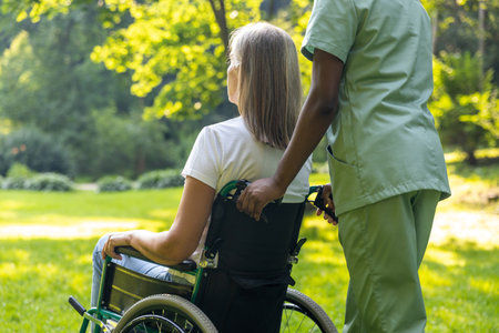 Nurse with a female patient on a wheelchair in the parkの写真素材