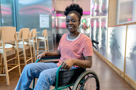Dark-skinned young smiling woman on a wheelchair looking positive