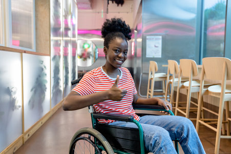 Dark-skinned young smiling woman on a wheelchair looking positive