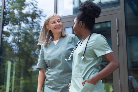 Two female doctors talking and looking contented and confidentの写真素材