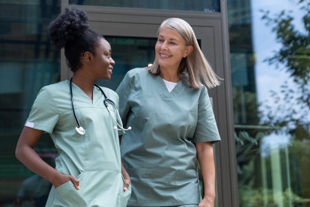Two female doctors talking and looking contented and confidentの写真素材