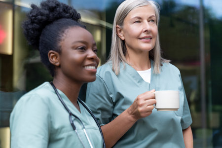 Two female doctors with cups with coffee in the elevator talkingの写真素材