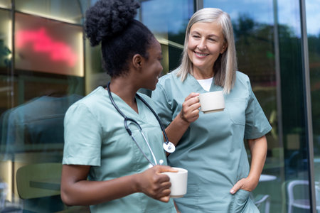 Two female doctors with cups with coffee in the elevator talkingの写真素材