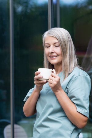 Mature caucasian female doctor having coffee and looking relaxedの写真素材