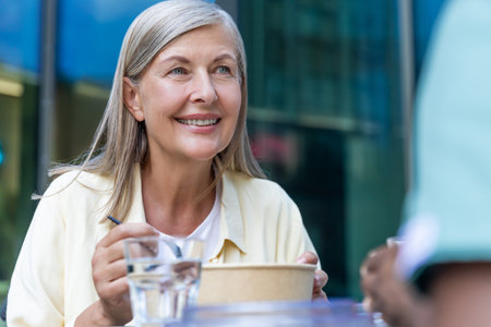 Nurse and a patient on a wheelchair having lunch together and talkingの写真素材