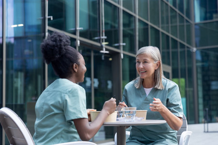 Female doctors having lunch together and looking involved while talkingの写真素材