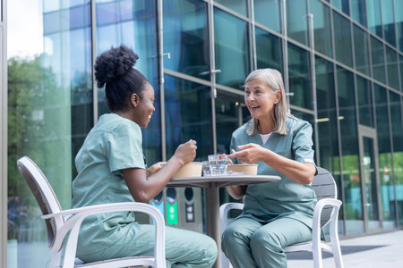 Female doctors having lunch together and looking involved while talkingの写真素材