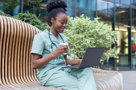 African american young doctor sitting on the bench and having coffeeの写真素材