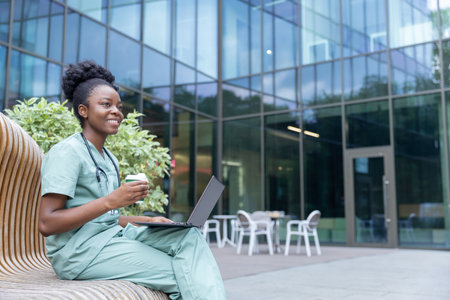 African american young doctor sitting on the bench and having coffeeの写真素材