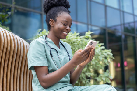 Young smiling african american woman in lab coat sitting on the benchの写真素材