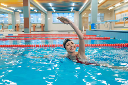 Cute caucasian young woman swimming in the pool with a boardの写真素材