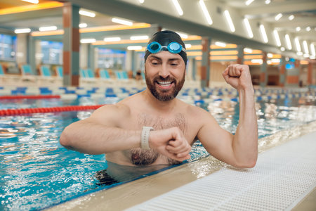 Man having a workout in the swimming pool and looking at his watchの写真素材