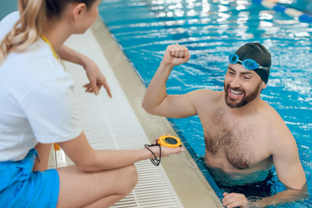 Man having a workout in the swimming pool and talking with his coach
