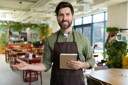 Male bearded waiter in pizzeria looking confident and smilingの写真素材