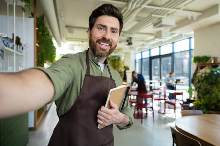 Male bearded waiter in pizzeria looking confident and smilingの写真素材