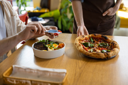Client getting his pizza in pizzeria and looking contented