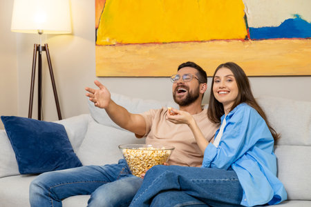 Young couple enjoying film on sofa with popcornの写真素材