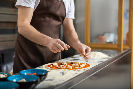 Man rolls dough in kitchen flattening carefully preparing pizza baseの写真素材