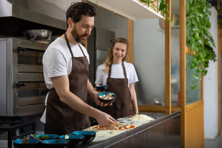 Man helps woman pizza in kitchen collaborating happily preparing mealの写真素材