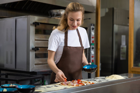 Woman adding toppings to pizzaの写真素材