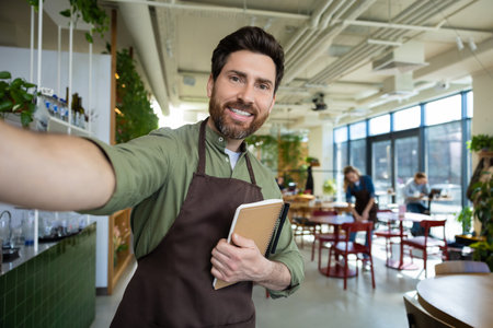 Smiling male waiter wearing apron take selfie looking at cameraの写真素材