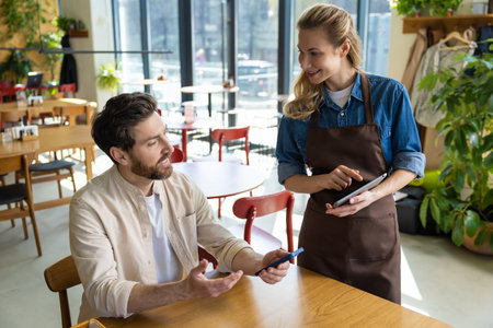 Waiter entering order on tablet at restaurantの写真素材