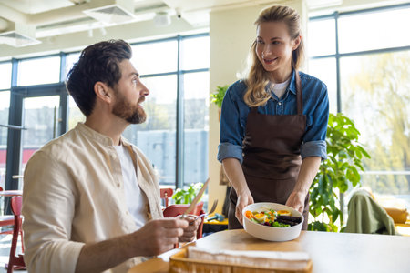 Waiter serving salad to man at restaurantの写真素材