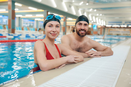 Young cute couple in swimwear in the swimming pool looking enjoyedの写真素材