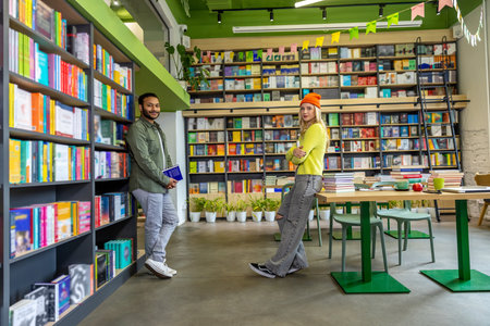 Man and woman reading in library surrounded by booksの写真素材