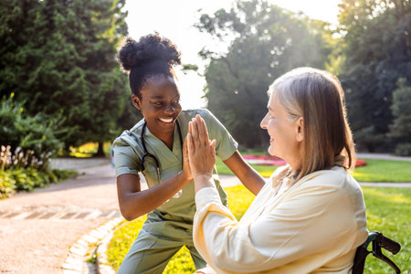 Caregiver and elderly woman sharing moment in park outdoorsの写真素材