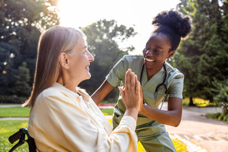 Elderly woman receiving care from nurse in park with greeneryの写真素材