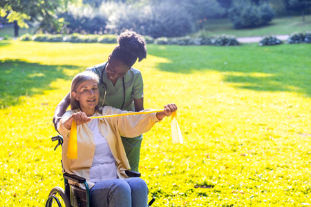 Caregiver assisting elderly woman in wheelchair in park sceneの写真素材