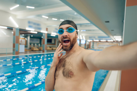 Young caucasian man in the swimming pool feeling excited and happyの写真素材