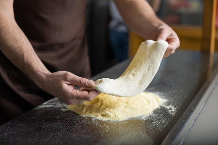 Close up of hands holding dough for pizza