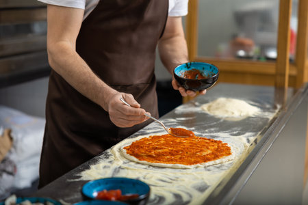 cooker putting filling into pizza in the kitchen