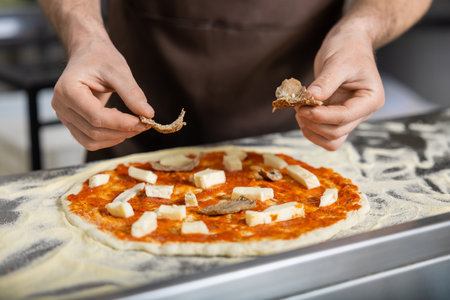 Close up picture of cookers hands putting topping o the pizzaの写真素材