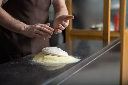 Close up of mans hands kneading dough for preparing pizza