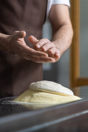 Close up of mans hands kneading dough for preparing pizza